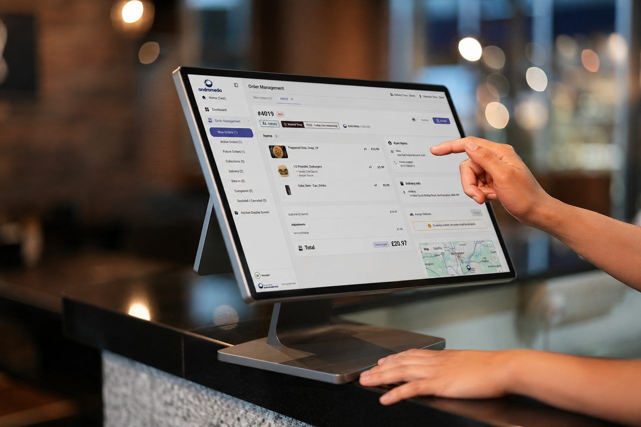 Andromeda POS in use behind the counter &mdash; order taking, kitchen tickets and live delivery on one platform